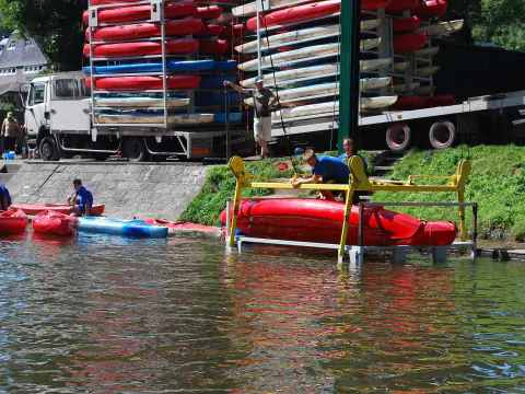 Kayaks rouges et bleus empilés sur un camion et amarrés au bord de l'eau à Anseremme